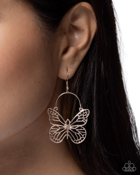 Butterfly-shaped earring worn by a person with dark hair.