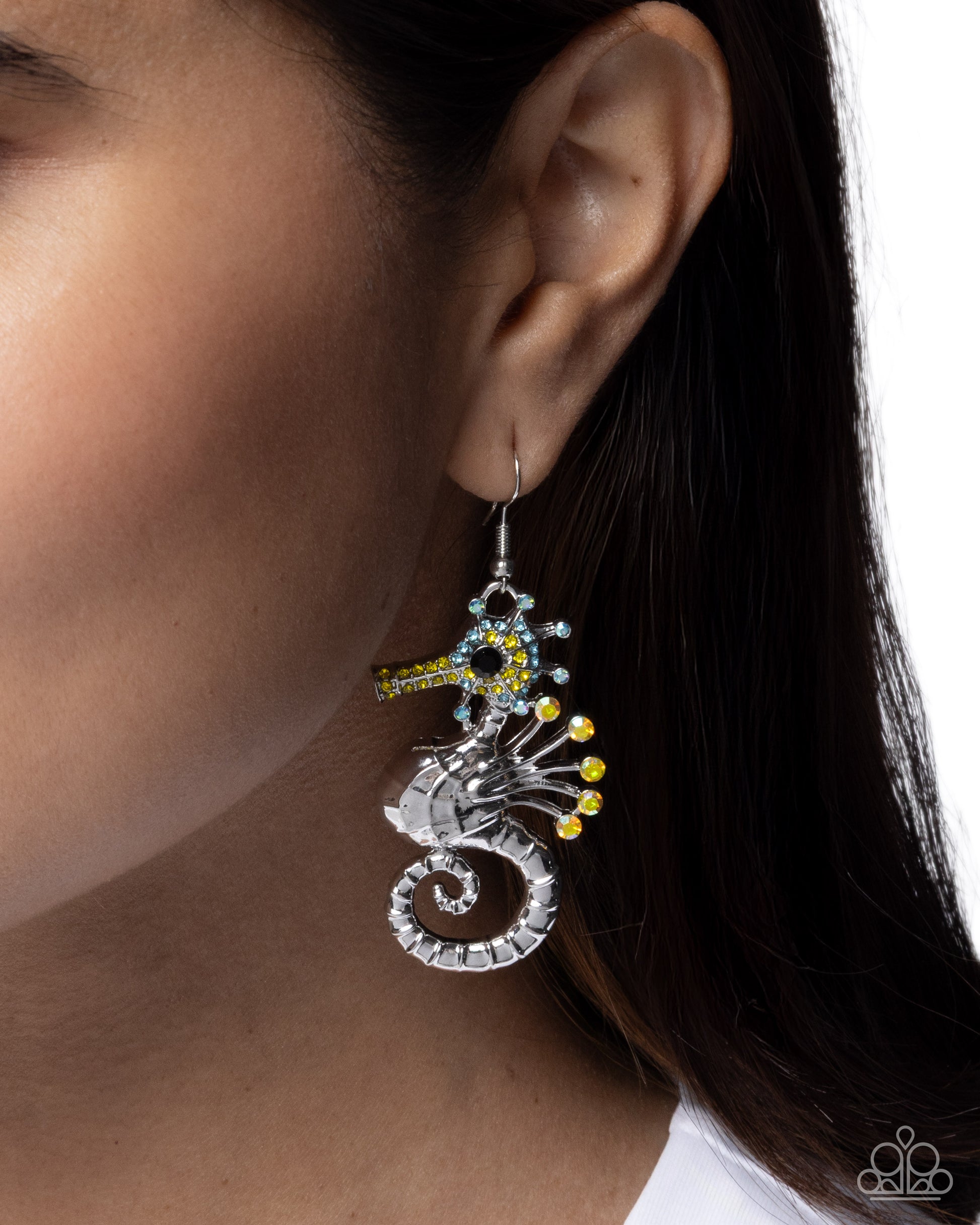 Close-up of an ear wearing a decorative earring with a seahorse design.