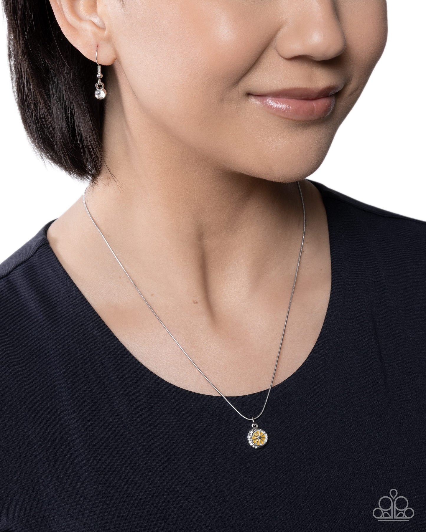 Woman wearing a silver necklace with a yellow pendant on a white background