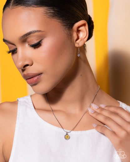 Woman wearing a necklace with a yellow pendant against a yellow background