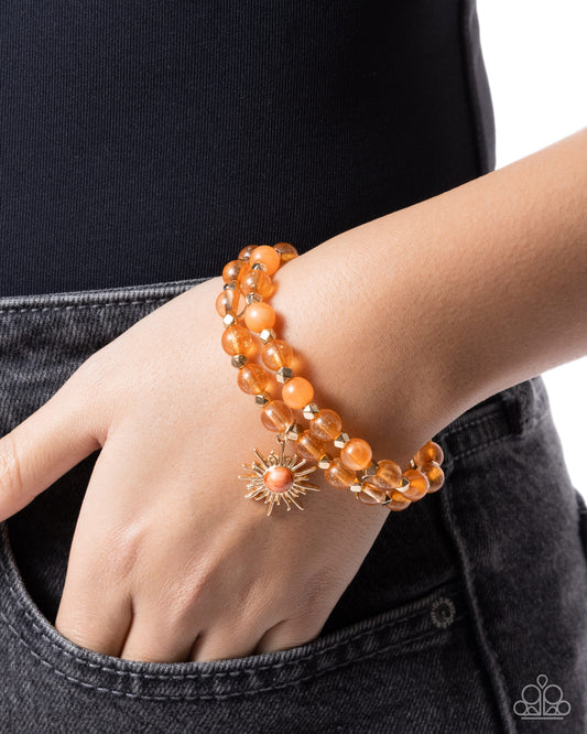 Orange beaded bracelet on a wrist with a black background