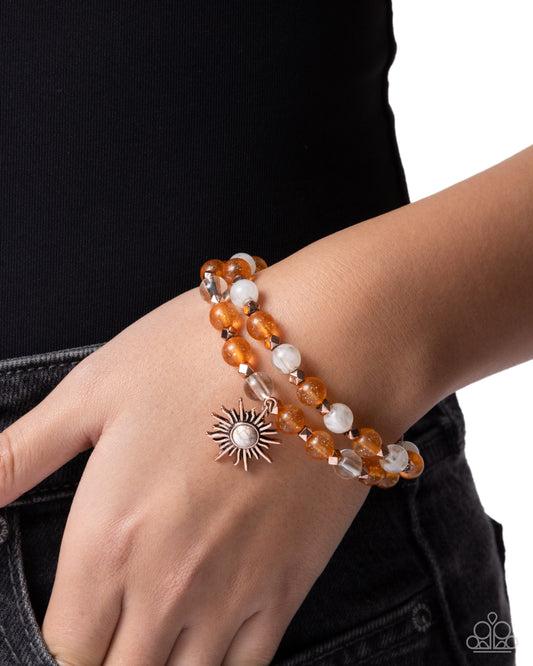 Bracelet with sun charm on wrist against a black background