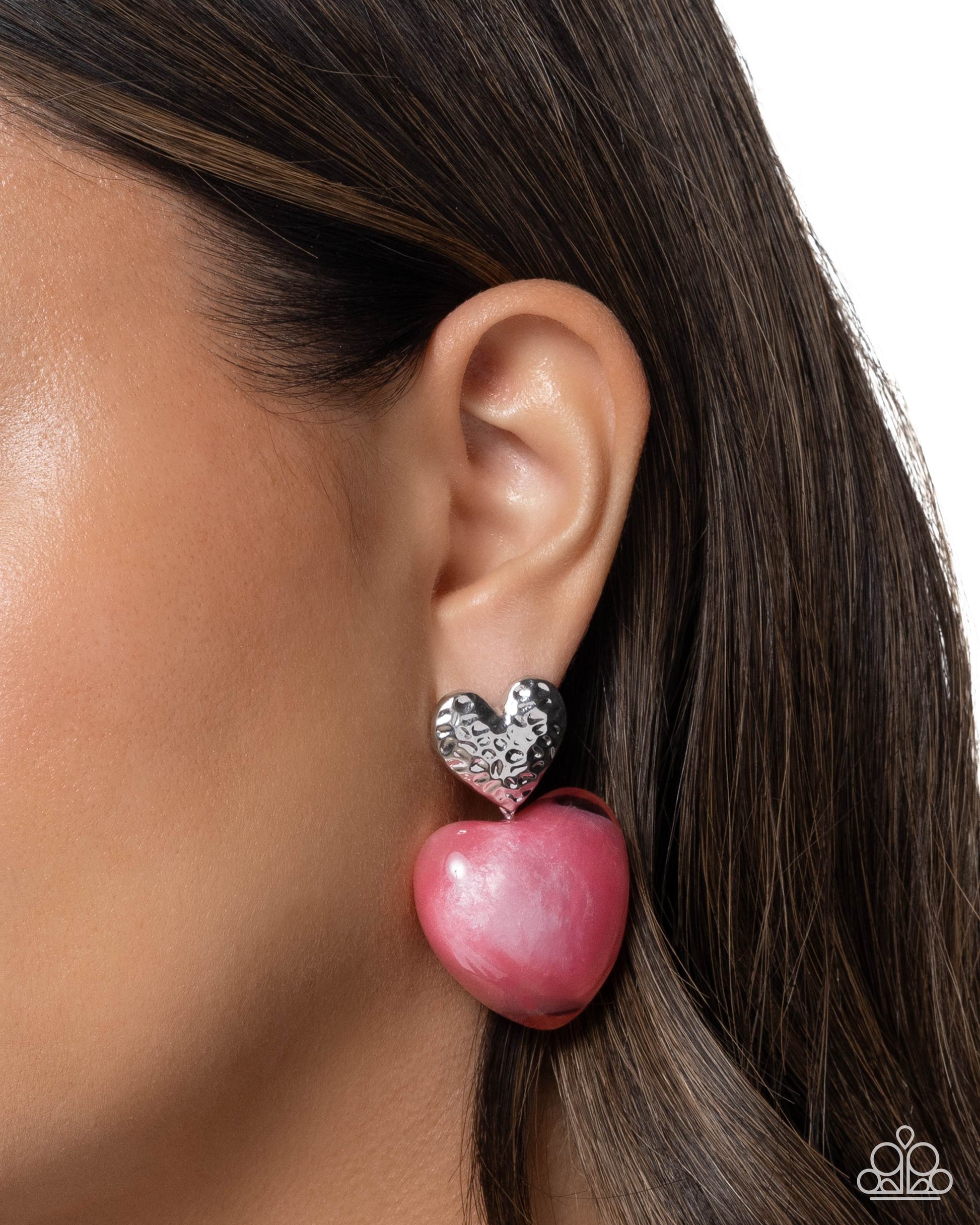 Pink heart-shaped earring worn by a model on a white background