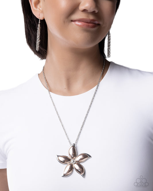 Woman wearing a silver flower pendant necklace and matching earrings on a white background