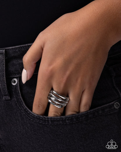 Hand wearing a silver ring on black denim background