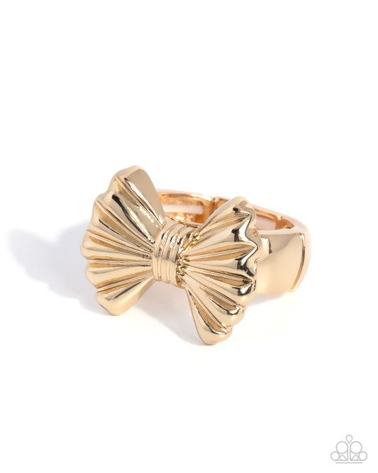 Gold bow-shaped ring on a white background