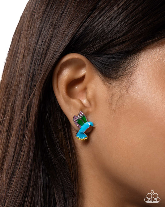 Close-up of an ear wearing a blue butterfly earring with green accents.