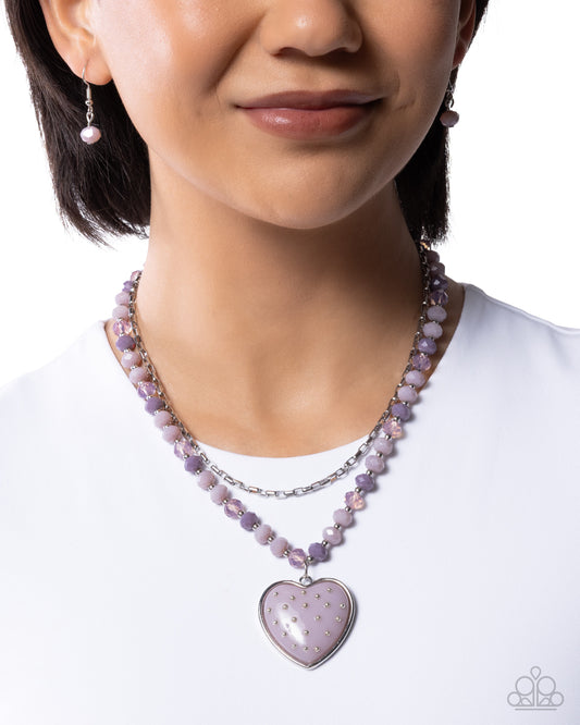 Person wearing a purple beaded necklace with a heart-shaped pendant on a white background