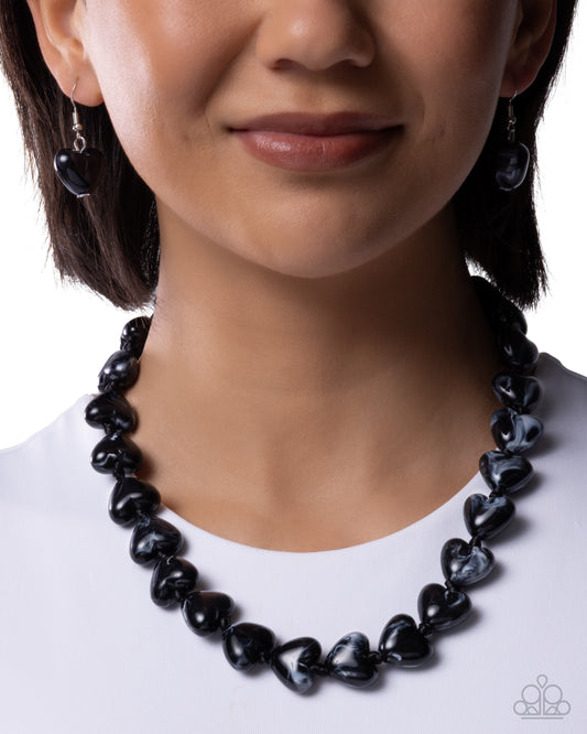 Black beaded necklace worn by a model on a white background
