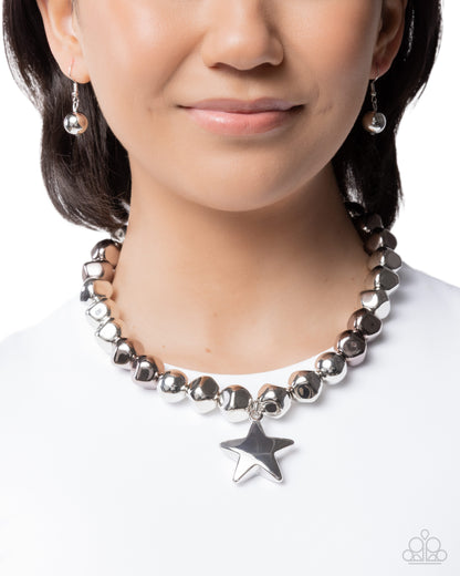 Person wearing a beaded necklace with star charm on a white background