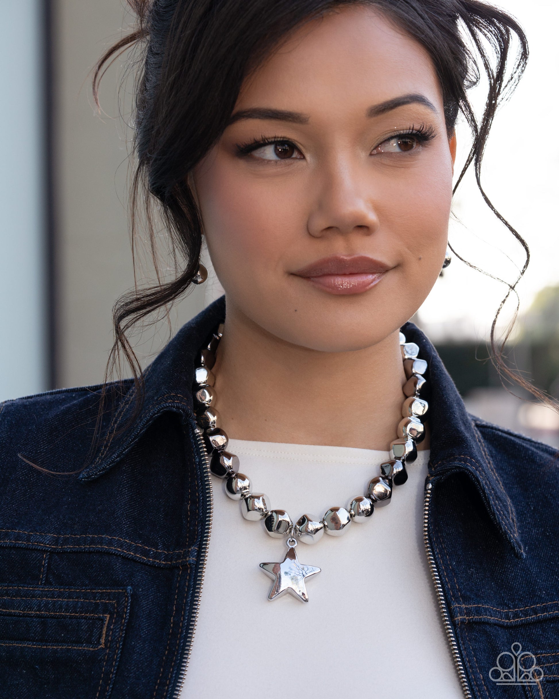 Woman wearing a star-shaped pendant necklace with a denim jacket