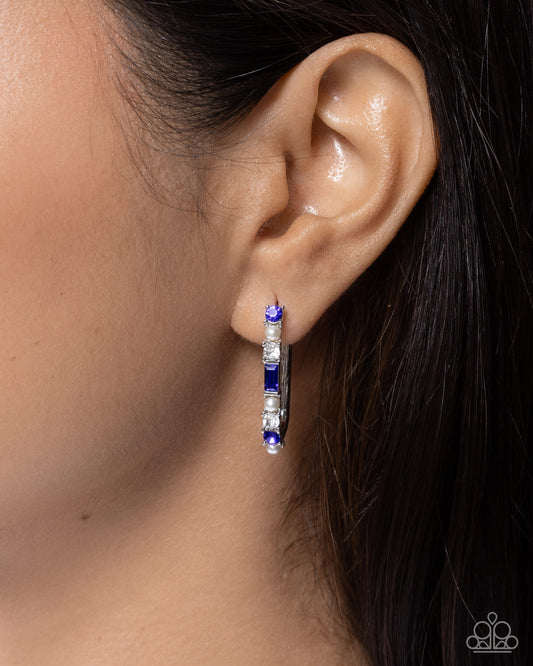 Close-up of an ear wearing a blue and silver hoop earring.