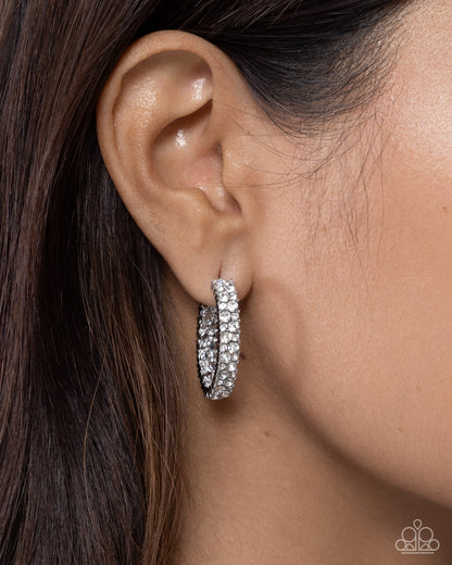 Close-up of an ear wearing a silver hoop earring with a blurred background