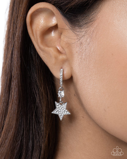Silver star-shaped earring worn by a person with dark hair.