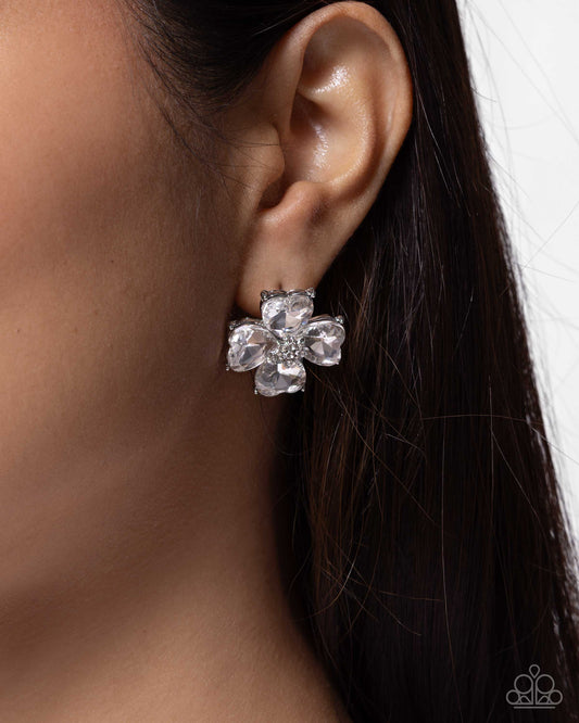 Close-up of an ear wearing a floral earring with clear stones.