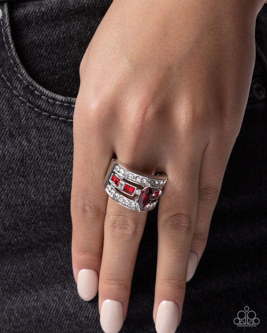 Silver ring with red gemstones on a hand against a dark background