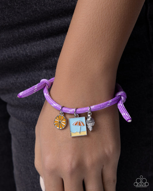 Purple bracelet with beach-themed charms on a wrist against a dark background