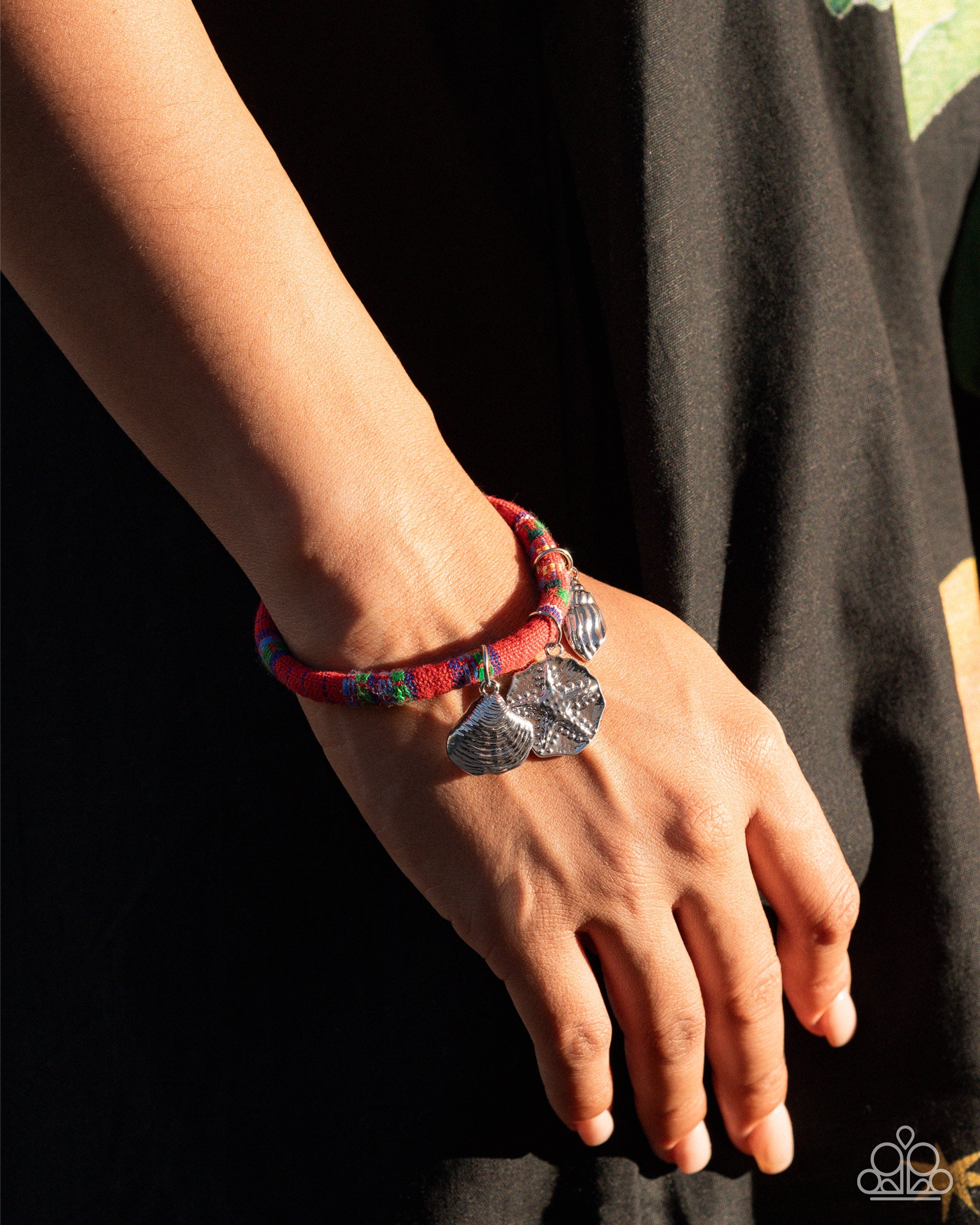 Bracelet with charms on a wrist against a black background