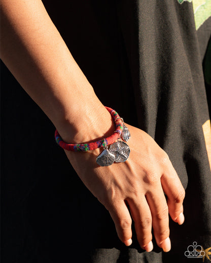 Bracelet with charms on a wrist against a black background