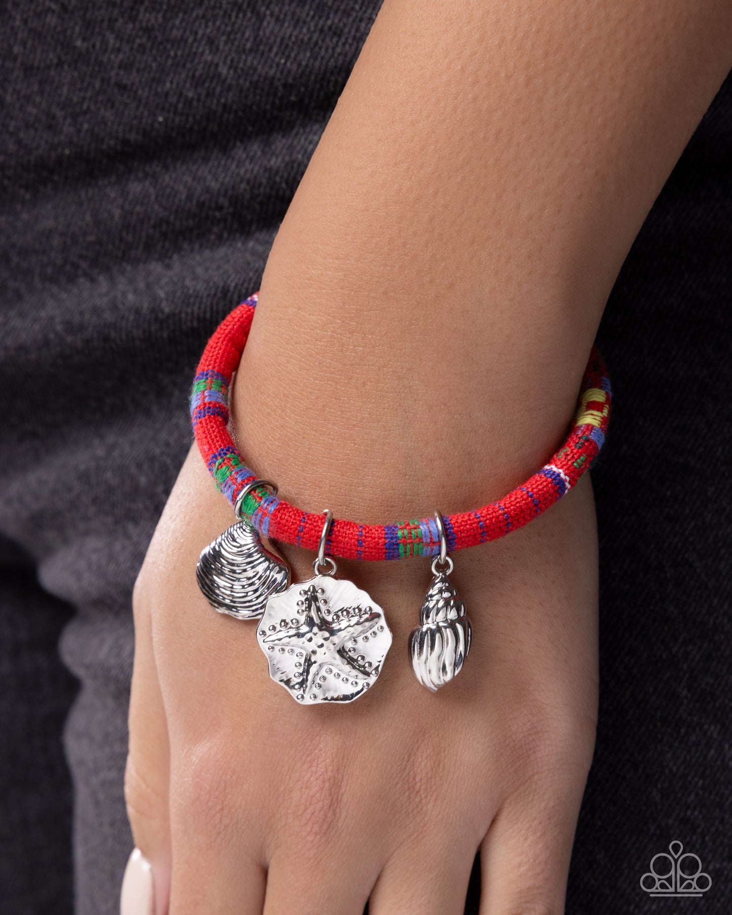 Bracelet with colorful beads and silver charms on a wrist against a dark background