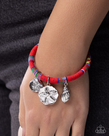 Bracelet with colorful beads and silver charms on a wrist against a dark background