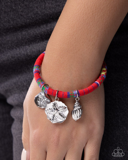 Bracelet with colorful beads and silver charms on a wrist against a dark background