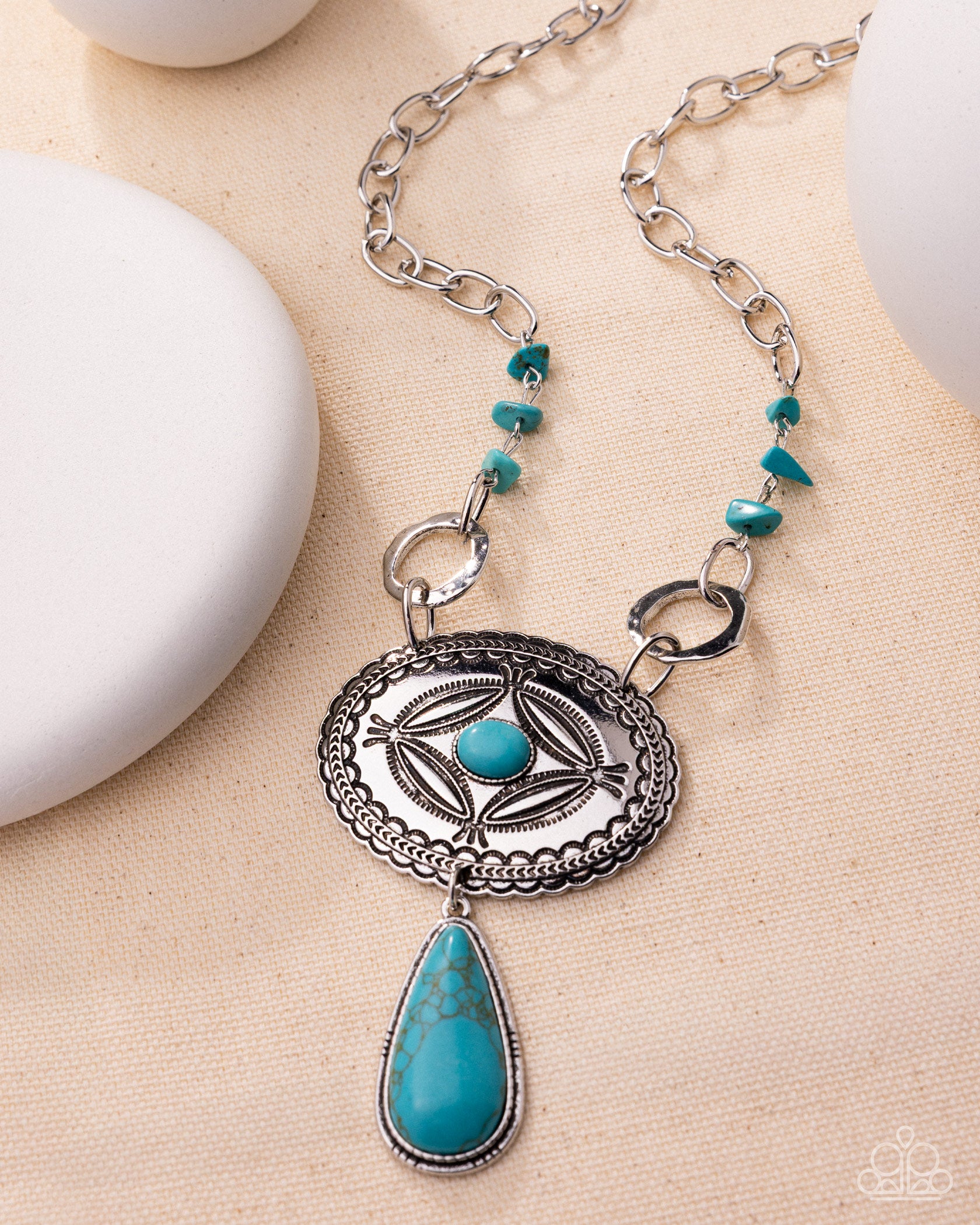 Necklace with silver and turquoise pendant on a beige surface