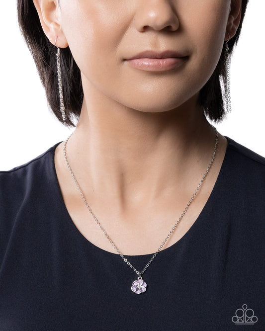 Close-up of a person wearing a silver necklace with a purple pendant on a white background