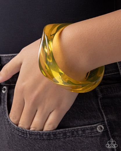 Yellow bangle on a wrist with a black background
