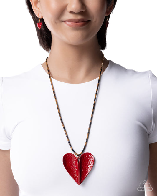 Person wearing a red heart-shaped pendant necklace on a white background