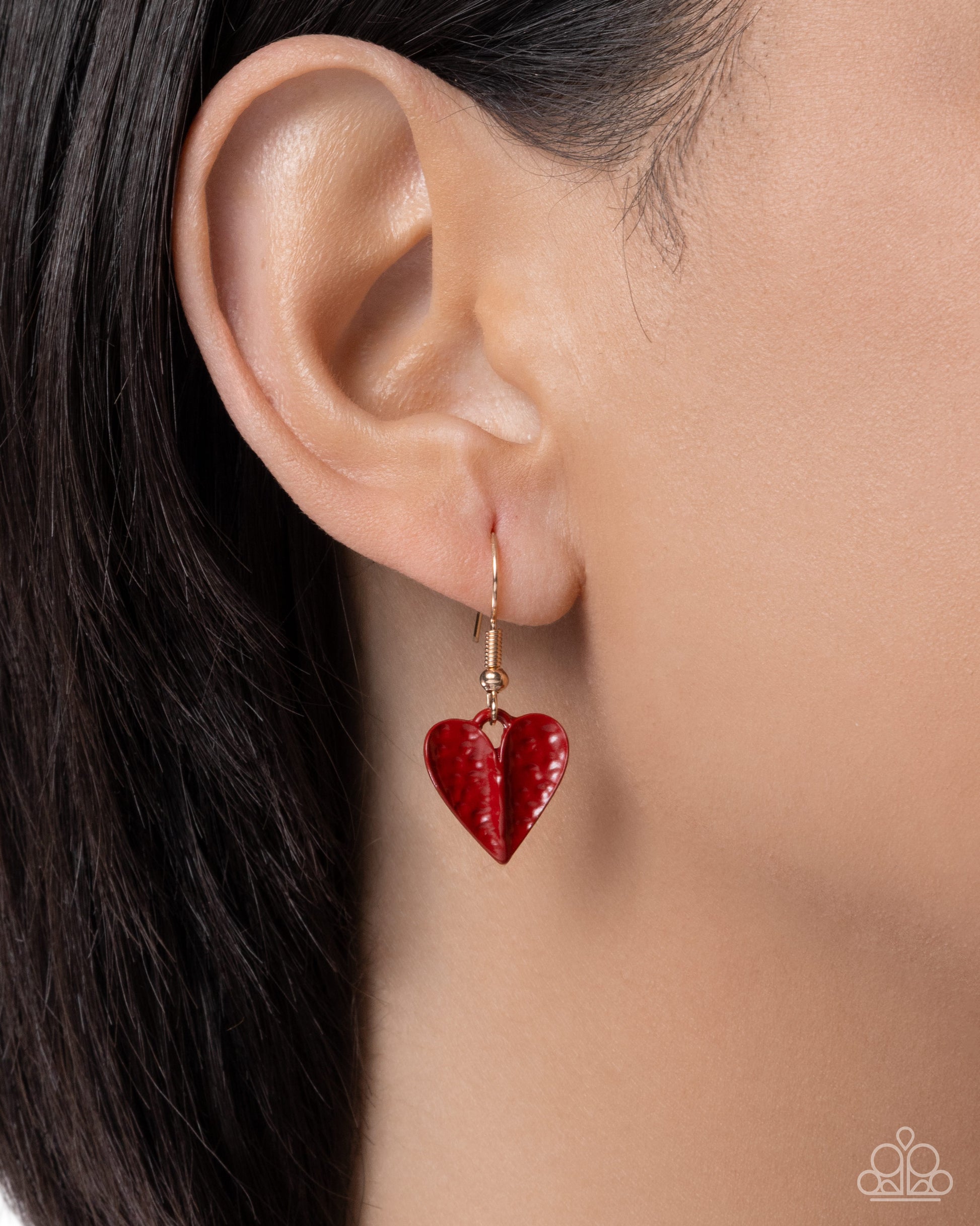 Red heart-shaped earring worn by a model with dark hair.