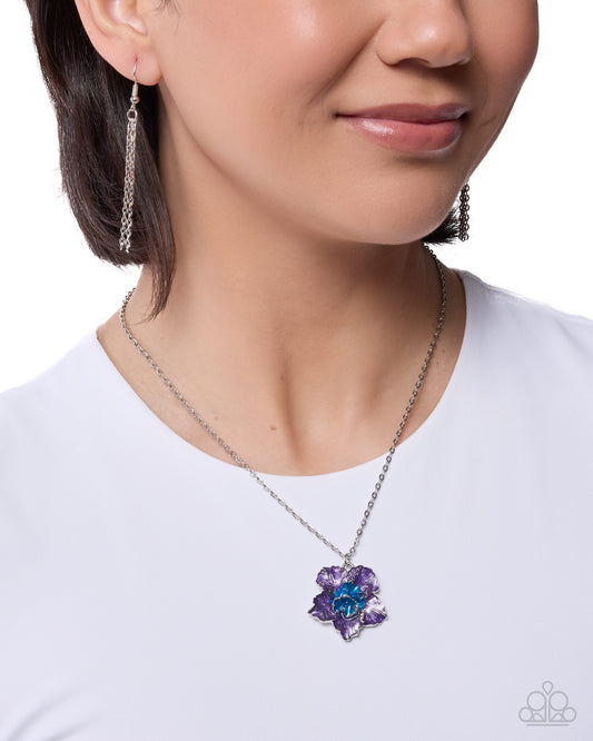 Necklace with a purple and blue flower pendant worn by a model on a white background