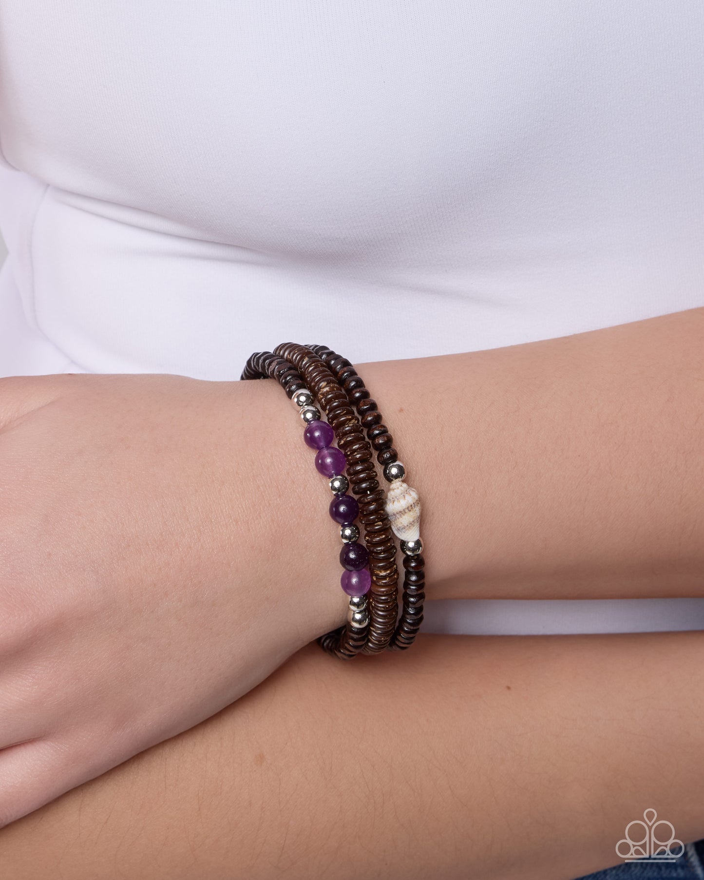 Stack of beaded bracelets on a wrist with a white background