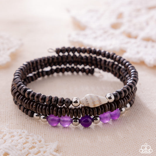 Black beaded bracelet with purple beads on a textured surface