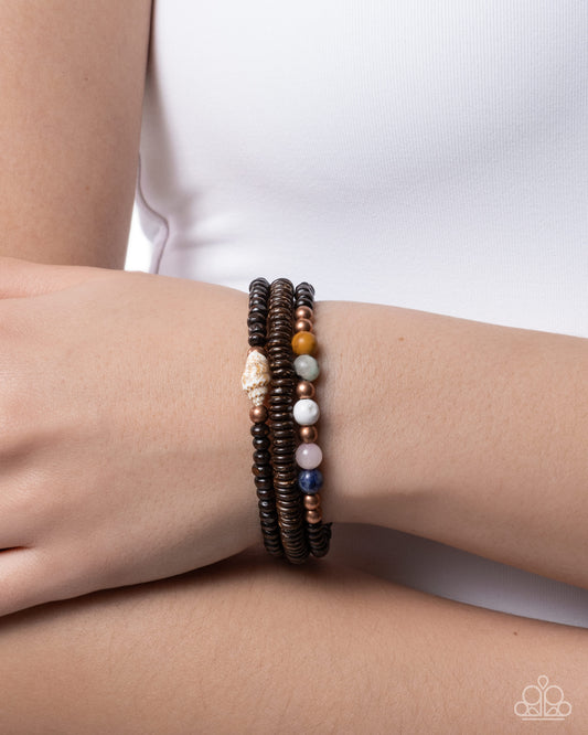 Stack of beaded bracelets on a wrist with a plain background