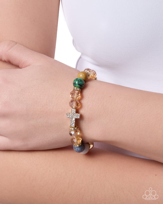 Multicolored beaded bracelet with a cross charm on a wrist against a white background