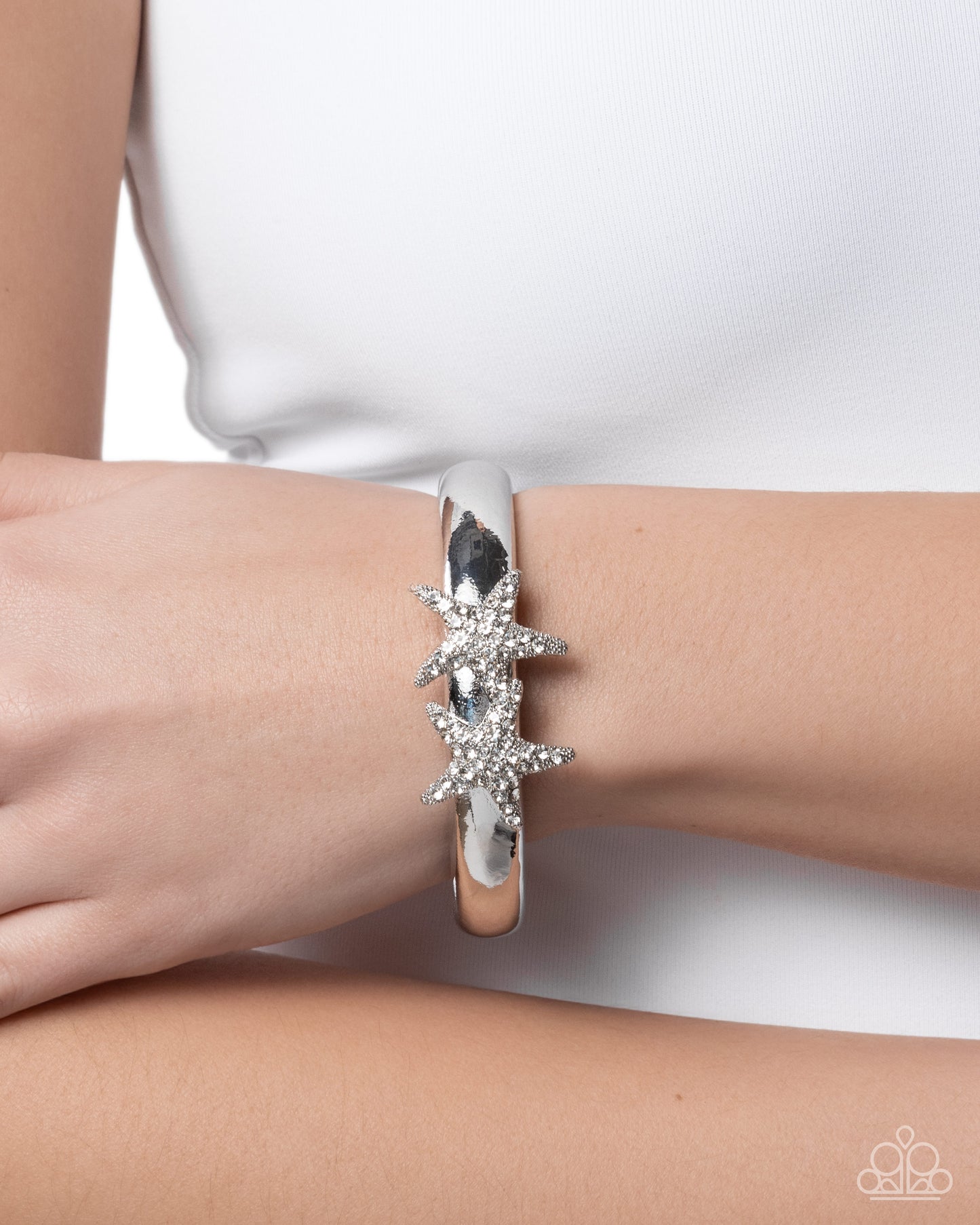 Silver bracelet with star design on a wrist against a white background