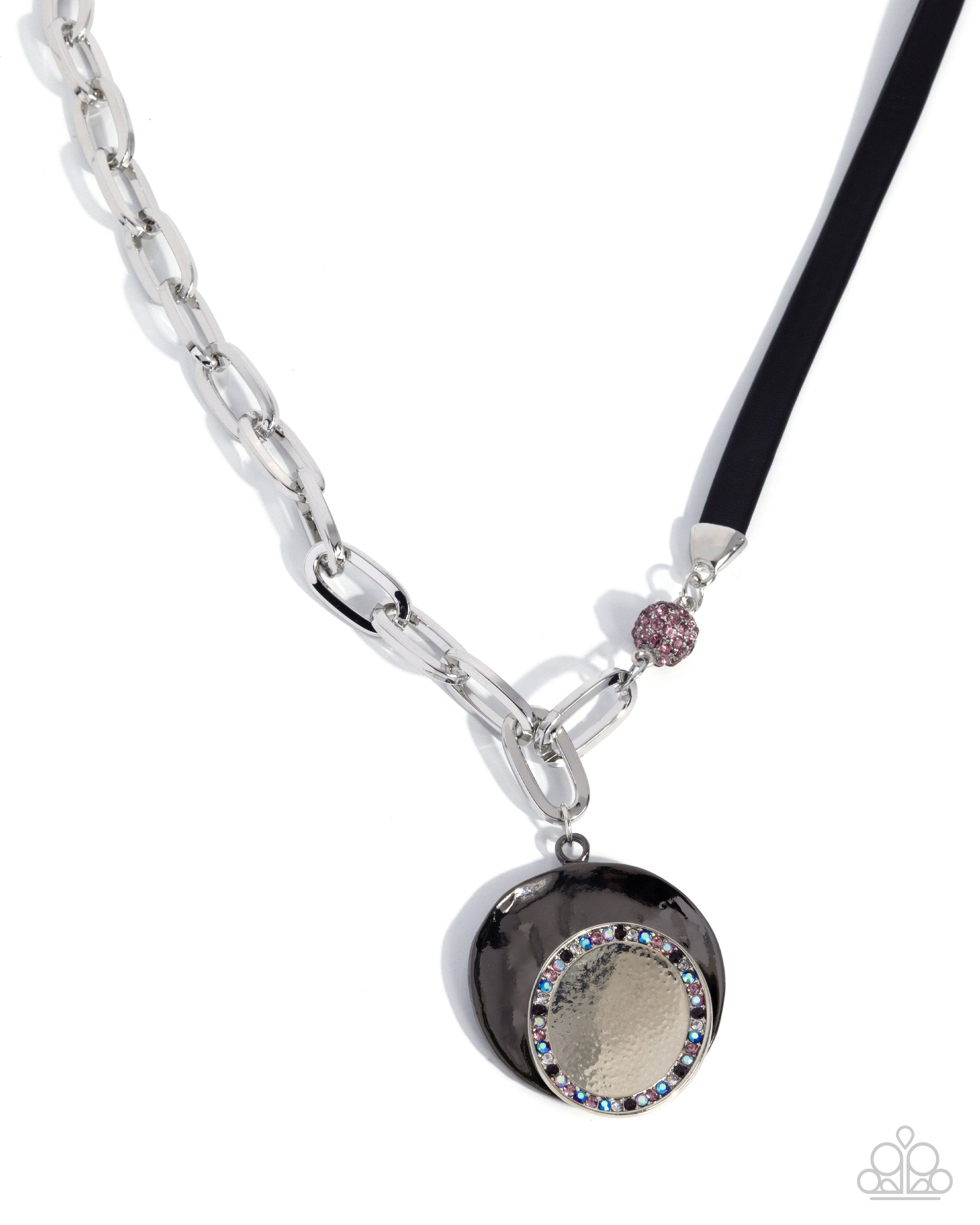 A silver-toned chain necklace with a black pendant featuring a textured gold center, a border of rhinestones, and a small pink rhinestone accent on a black cord, shown on a white background.
