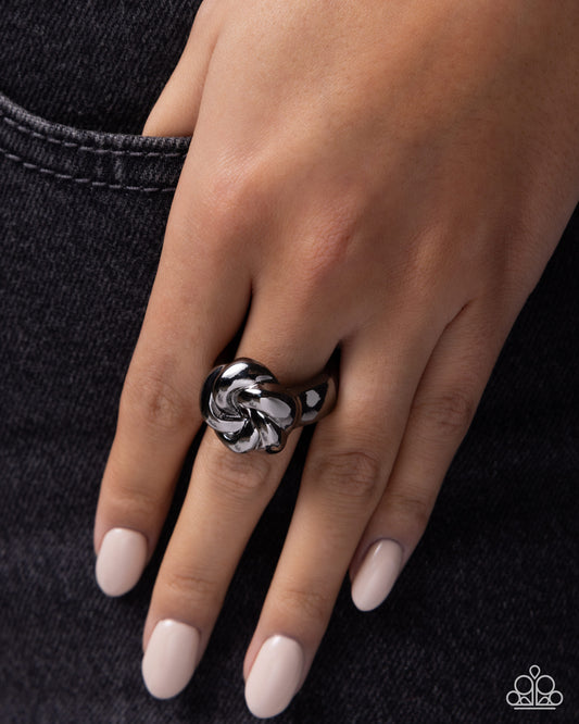 Close-up of a hand wearing a silver ring on a dark background