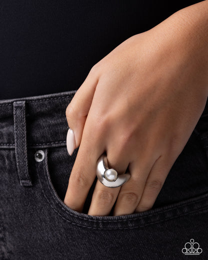 Hand wearing a silver ring on a black background