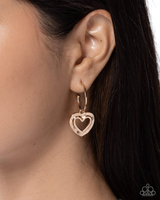 Heart-shaped earring worn by a person with dark hair.