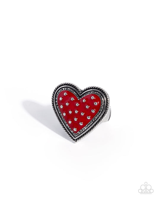 Red heart-shaped ring with silver accents on a white background