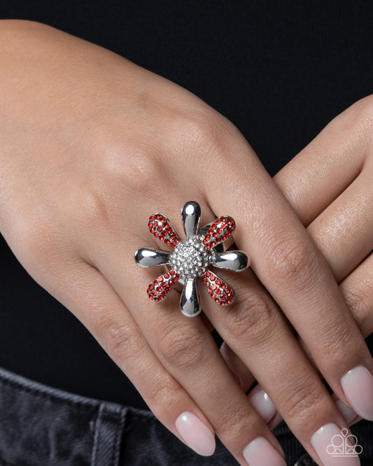 Silver ring with red gemstones on a hand against a black background
