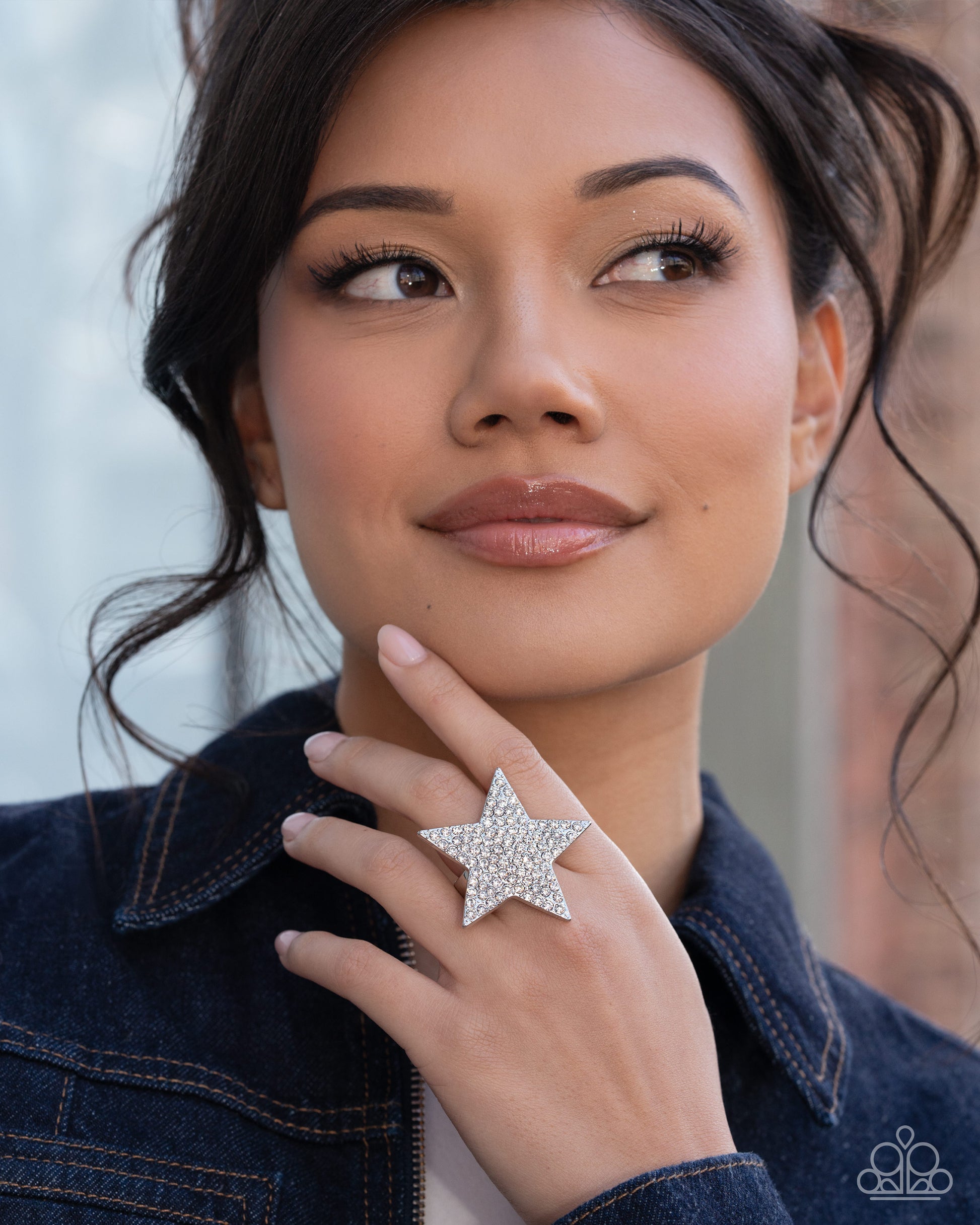 Woman wearing a star-shaped ring with a blurred outdoor background