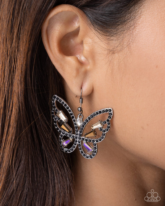 Butterfly-shaped earring worn by a person with brown hair.
