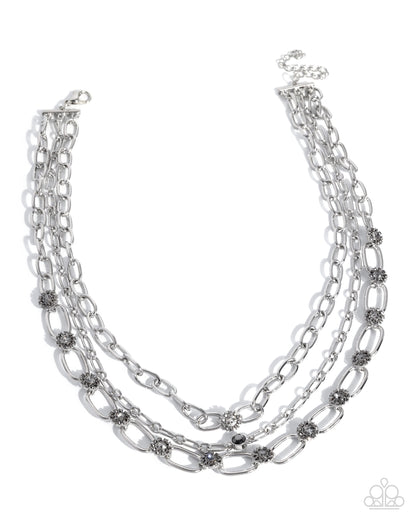 Multi-layered silver chain necklace with small embellishments on a white background