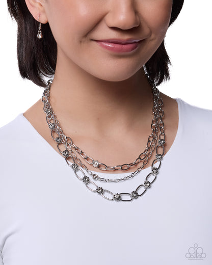 Woman wearing a layered silver chain necklace on a white background