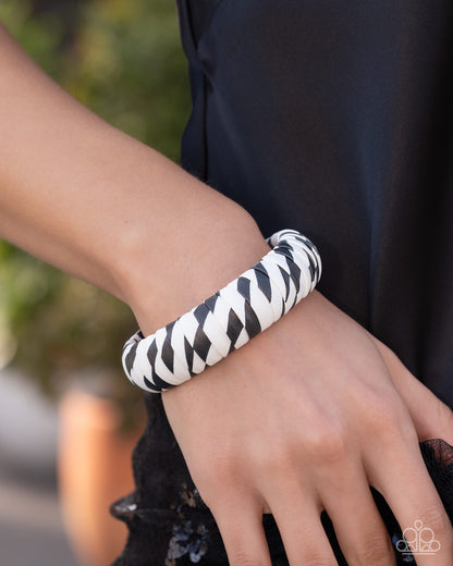 Person wearing a black and white zebra patterned bracelet on a blurred background
