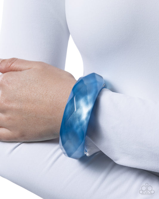 Blue bangle on a wrist with a white background
