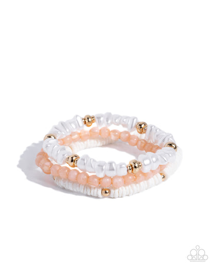 Set of white and peach beaded bracelets with gold accents on a white background